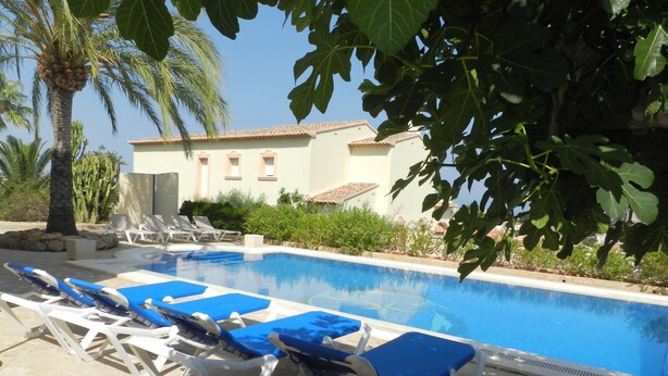 A swimming pool with lounge chairs and a building in the background. - Villa Fig Tree Para 4 Personas (Calpe)