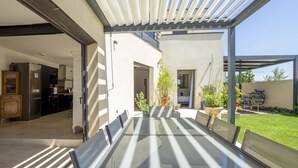 A modern kitchen with stainless steel appliances and a dining area with a glass table and chairs. - Maison des Fleurs in Ved ne (Vedene)