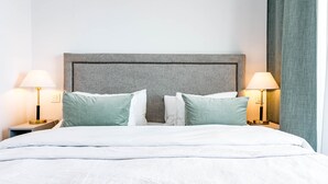 A neatly made bed with white linens, two bedside tables with lamps, and a grey headboard. - OV2 1B - Bright and Modern 3 Bedroom Apartment (Estepona)