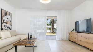 A modern living room with a sofa, coffee table, TV, and a sliding glass door leading to an outdoor area. - Ags48b- Great Location Close to Puerto Banus Casa (Marbella)