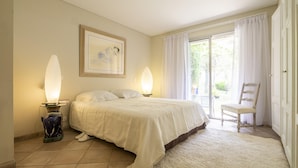 Una camera da letto con un letto, due abat-jour, una sedia e un'ampia finestra con tende.