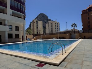Piscina con vista chiara su una montagna sullo sfondo, circondata da edifici moderni.