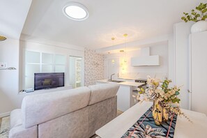 A modern living room with a sofa, a television, and a dining area with a table and vase. - Colon 904 in Madrid With 1 Bedrooms and 1 Bathrooms (Madrid)