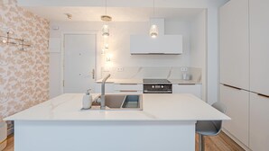 A modern kitchen with a central island, pendant lighting, and a built-in oven.
