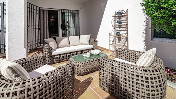 A patio with wicker furniture, a glass-top table, and a white sofa. - SDG 2B - Holiday Home Senorio de Gonzaga (Marbella)