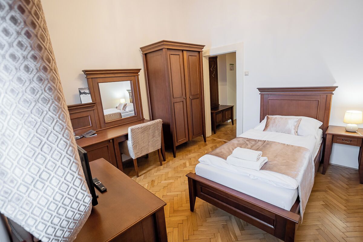 Ett hotellrum med en säng, ett skrivbord, en stol, en garderob och en spegel.