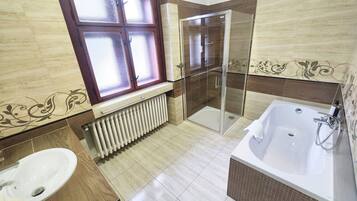 Un baño con ducha, bañera, ventana y radiador.