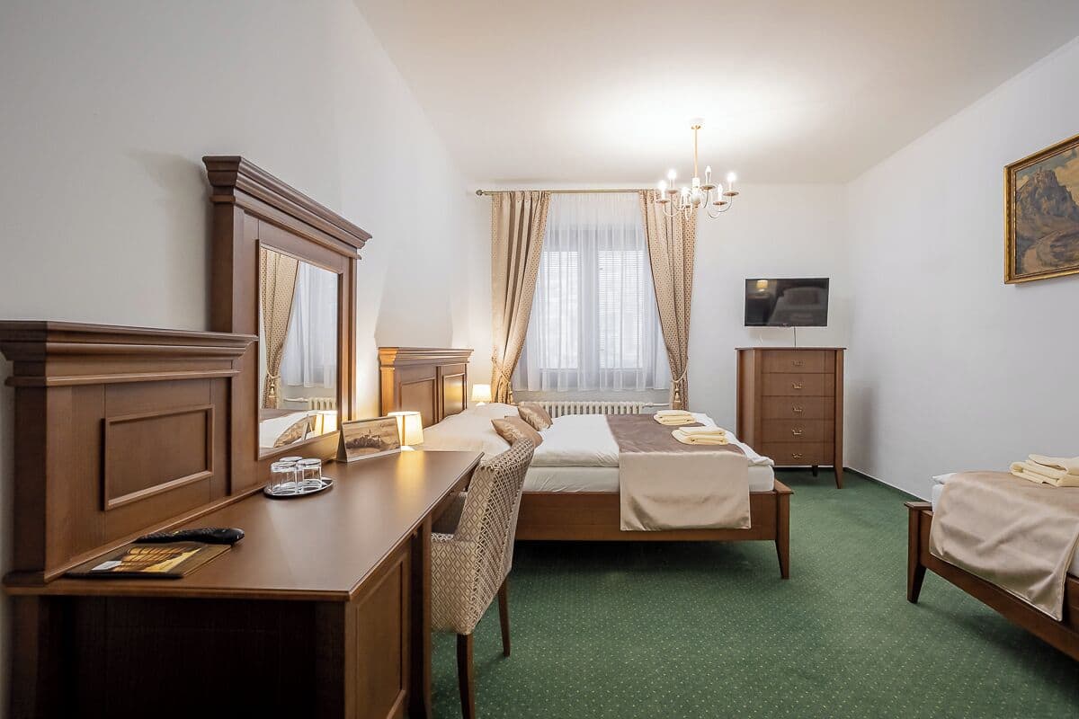 A hotel room with a bed, a desk, a chair, a dresser, a television, and a painting on the wall.