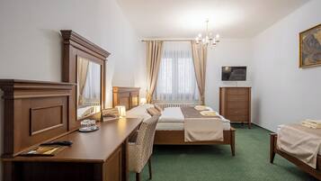 Une chambre d’hôtel avec un lit, un bureau, une chaise, une commode, un téléviseur et un tableau au mur.