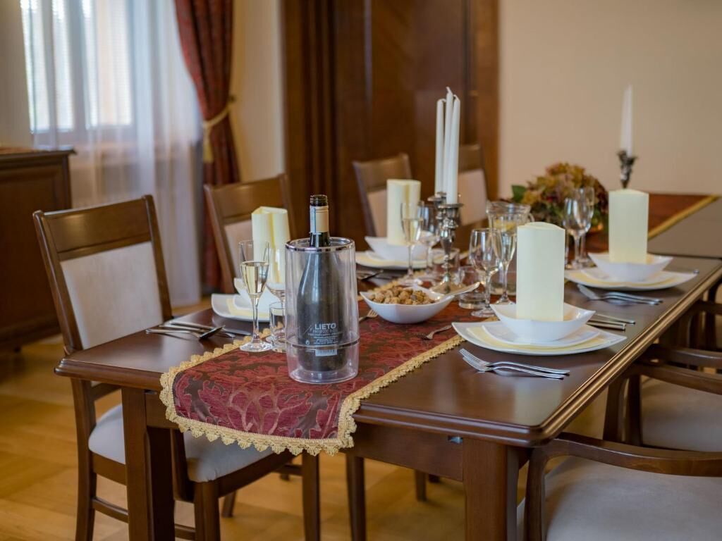 Una mesa de comedor dispuesta con platos blancos, vasos y un candelabro.