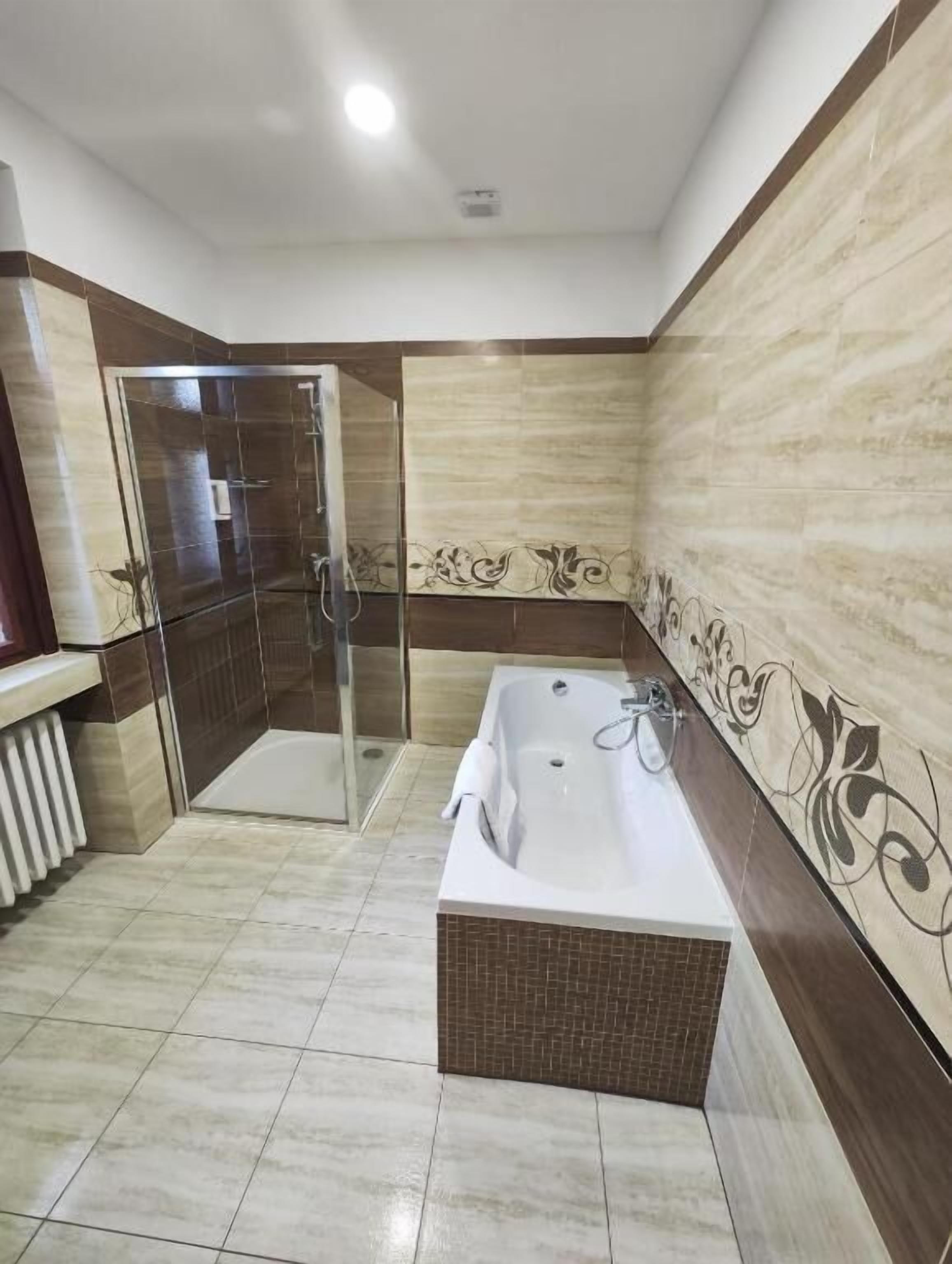 Un baño con cabina de ducha de vidrio, bañera independiente y suelo de baldosas.
