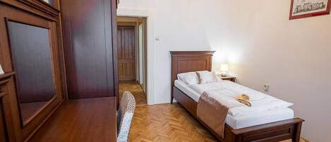 A bedroom with a wooden bed, a desk, and a chair.