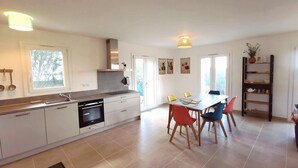 Een moderne keuken met een eethoek, met een groot raam, een ingebouwde oven en een eettafel met stoelen.