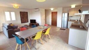 Een modern appartement met een eethoek, keuken, woonkamer en een groot raam.