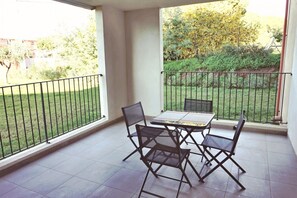 A balcony with a table and chairs, a view of a garden, and a railing. - Mor102 - Appartement vue mer - 100m de la Plage (Saint-Florent)