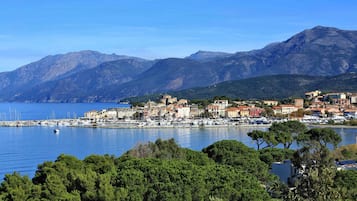 A coastal town with a marina, buildings, and mountains in the background.