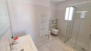 A modern bathroom with a glass shower enclosure, a white sink, and a toilet. - Mor401 - T5 Neuf Piscine vue mer Panoramique (Saint-Florent)