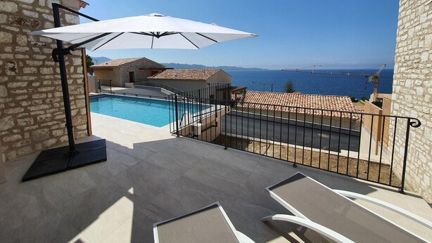 A rooftop pool area with a clear view of the sea and mountains in the background. - Mor401 - T5 Neuf Piscine vue mer Panoramique (Saint-Florent)