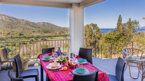 Un balcón con mesa lista para comer, con vista a un paisaje montañoso.