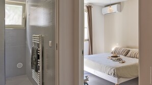 Un dormitorio con cama, ventana, aire acondicionado y un toallero.