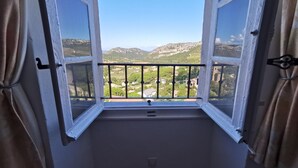 A window with open shutters, offering a view of a green landscape with hills and buildings. - Appartement Palazzo T2 Patrimonio (Patrimonio)