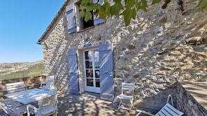 A stone building with a patio area featuring white furniture and a view of the countryside. - Appartement Palazzo T2 Patrimonio (Patrimonio)