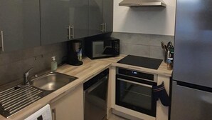 A compact kitchen with a washing machine, a microwave, an oven, and a refrigerator. - Appartement T3 Luccia Proche Saint Florent (Oletta)