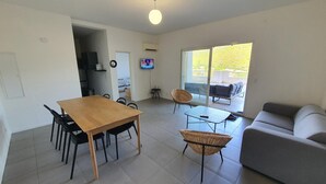A modern living space with a dining area, a sofa, and a balcony with outdoor furniture. - Appartement T3 Luccia Proche Saint Florent (Oletta)