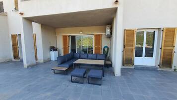 An outdoor seating area with a sofa and table, a refrigerator, and a view of the landscape.