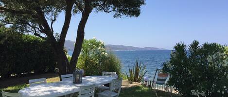 A white outdoor dining set with a view of the sea and mountains.