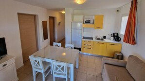 Een knus woongedeelte met een eethoek, kitchenette en een bank.
