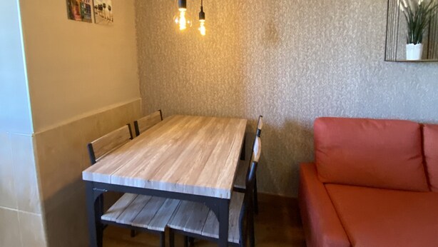 Ein Essbereich mit Holztisch und Stühlen, einem roten Sofa und einer Hängeleuchte.