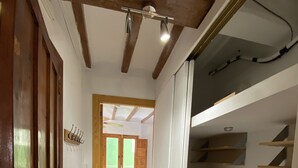 Ein schmaler Korridor mit Holzboden, einer weißen Tür links und einem weißen Schrank rechts.