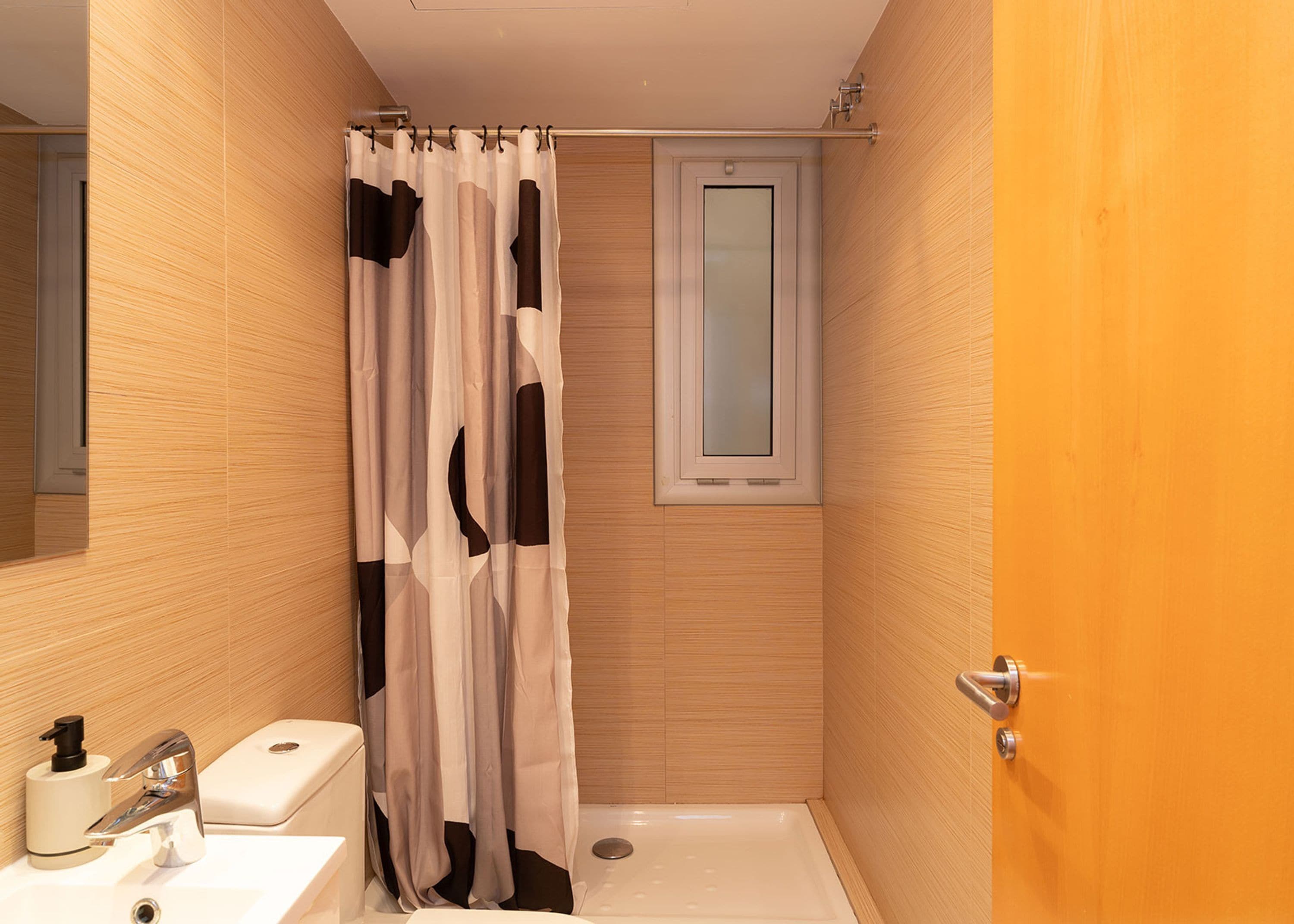 A small, modern bathroom with a shower, toilet, and sink.