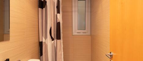 A small, modern bathroom with a shower, toilet, and sink.