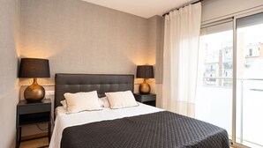 A modern hotel room with a large bed, two bedside tables with lamps, a large window with curtains, and a city view.