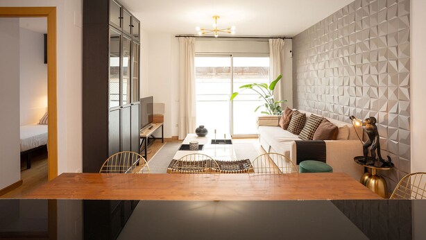 A modern living room with a wooden dining table, a sofa, and a decorative statue.