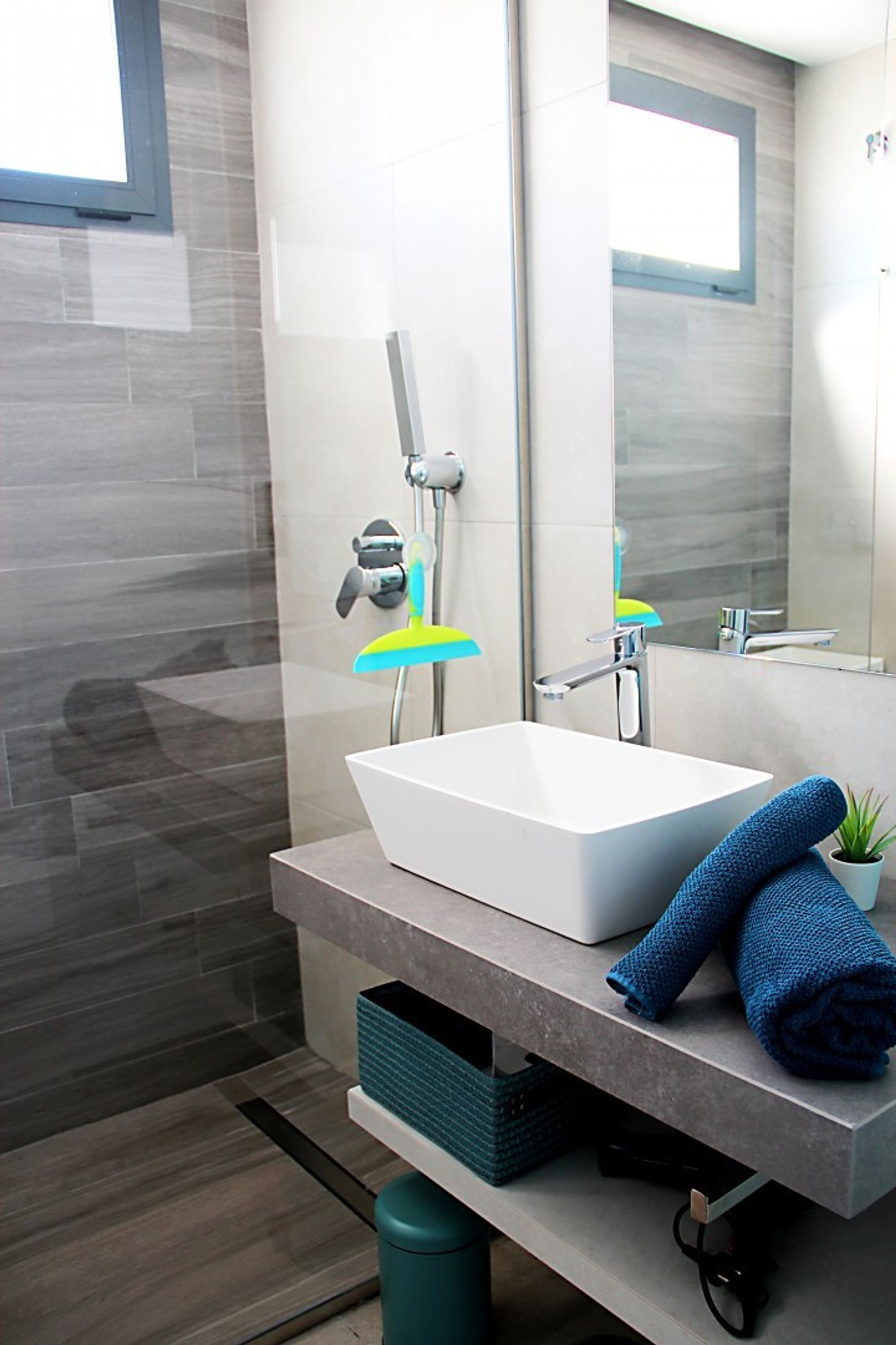 Ein modernes Badezimmer mit Waschbecken, Spiegel und Fenster.