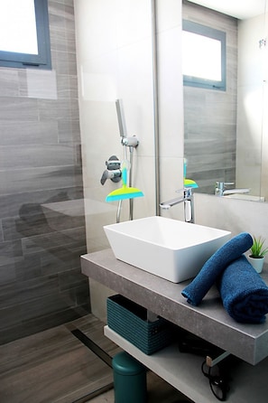 A modern bathroom with a white sink, a mirror, and a window.