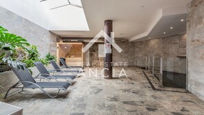 A spacious indoor area with a high ceiling, a central column, and a row of lounge chairs along one wall. - Casa Rosa in Guardamar (Guardamar del Segura)