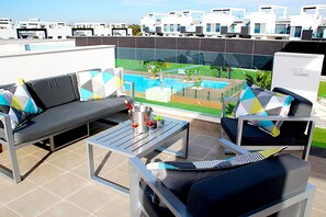 A rooftop terrace with a pool, outdoor seating, and a view of modern buildings. - Casa Rosa in Guardamar (Guardamar del Segura)