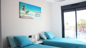 A hotel room with two beds, a painting of a beach scene, and a large window offering a view of palm trees. - Casa Rosa in Guardamar (Guardamar del Segura)