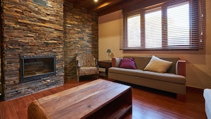 A living room with a stone fireplace, wooden coffee table, and a sofa with cushions.