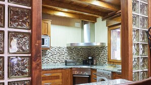 A kitchen with a brick wall, wooden cabinets, and a granite countertop.