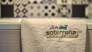 A towel with embroidered text and a logo, placed on a window sill with a patterned curtain in the background. - AV Soterra a 3B in Vila (Ávila)