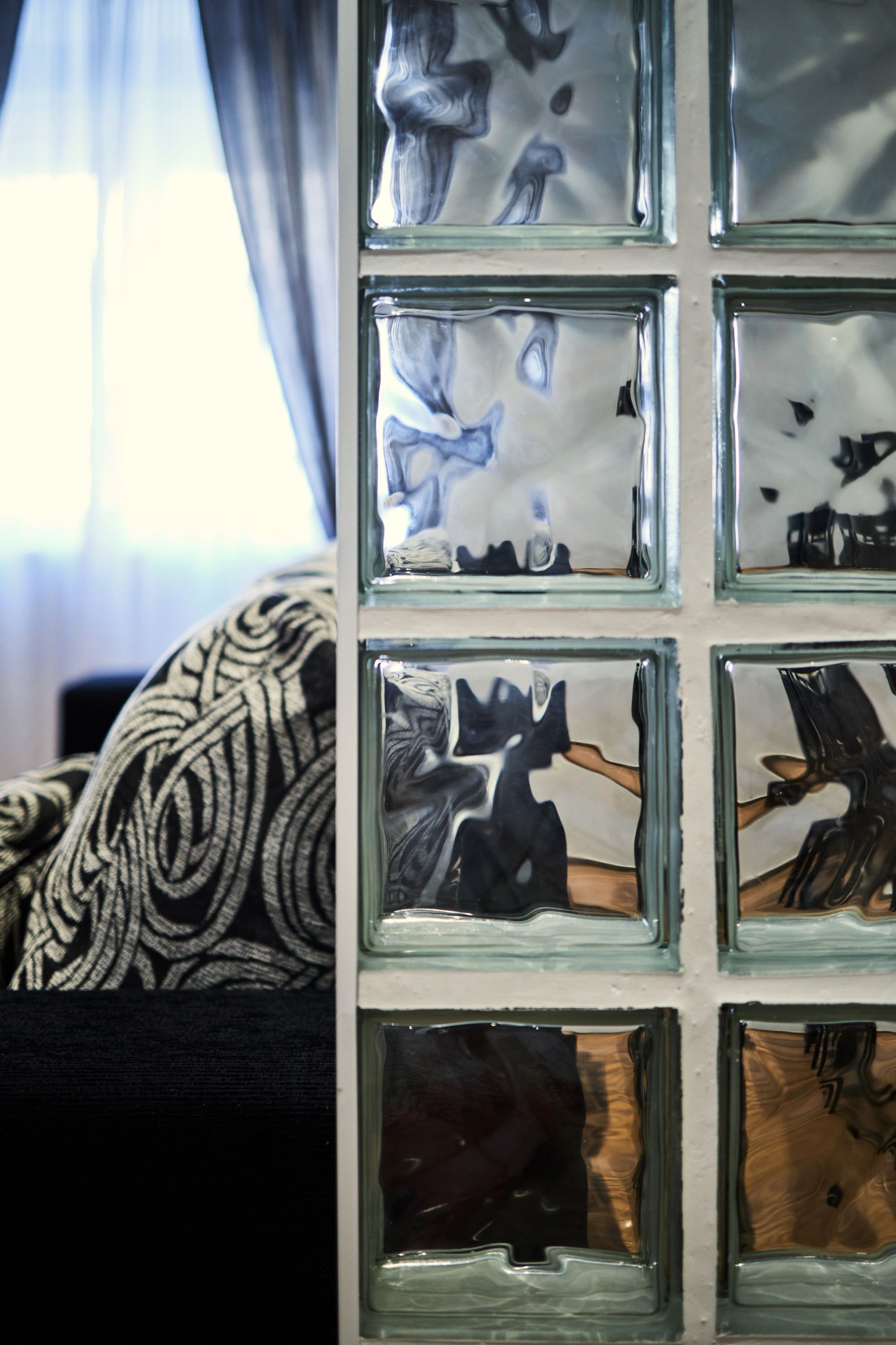 Un mur composé de plusieurs panneaux de verre carrés, chacun présentant un motif abstrait unique.