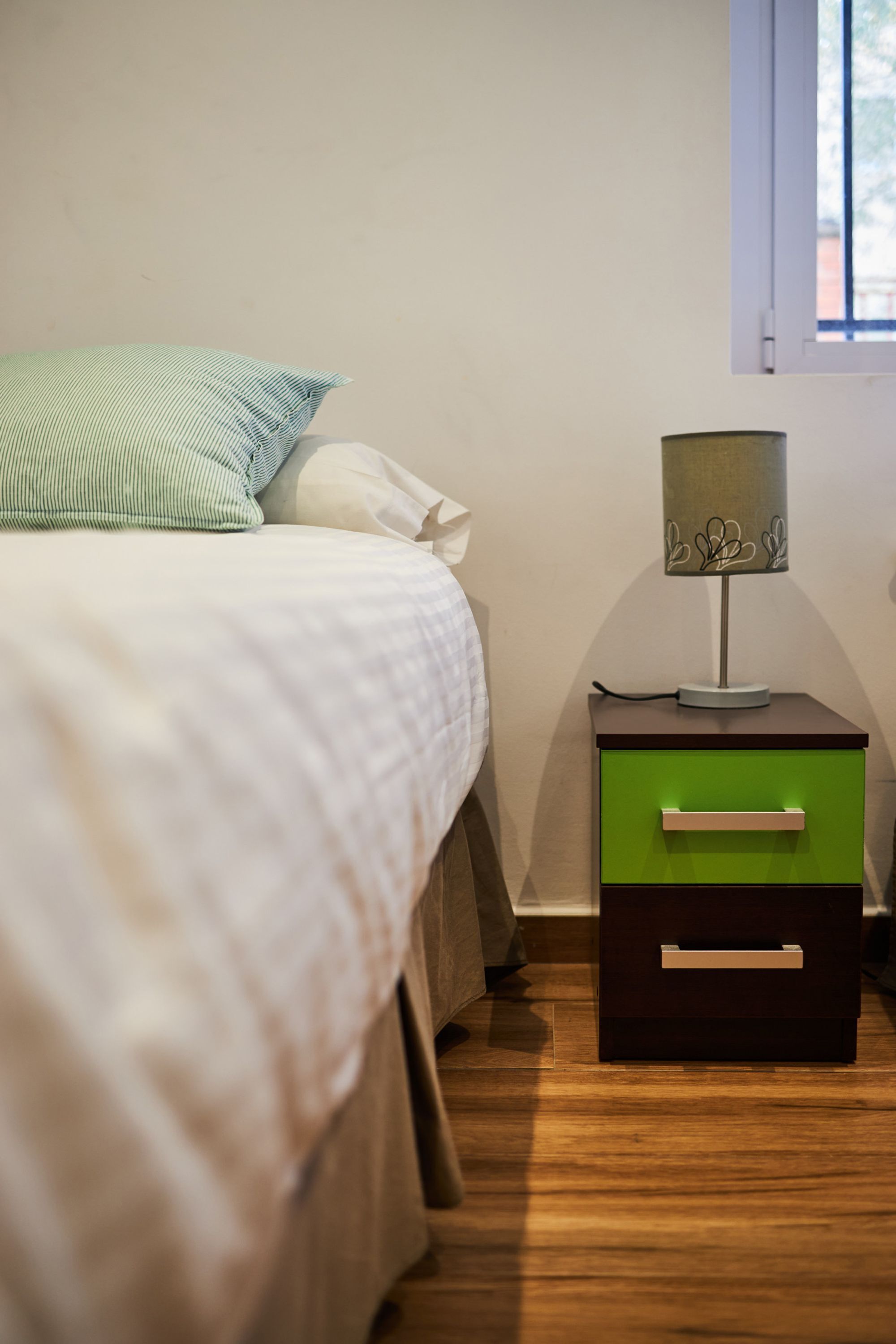 Une chambre à coucher avec un lit, une table de chevet avec une lampe et une commode verte.