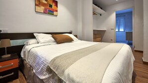 Une chambre à coucher moderne avec un grand lit, une table de chevet, une commode et un tableau au mur.