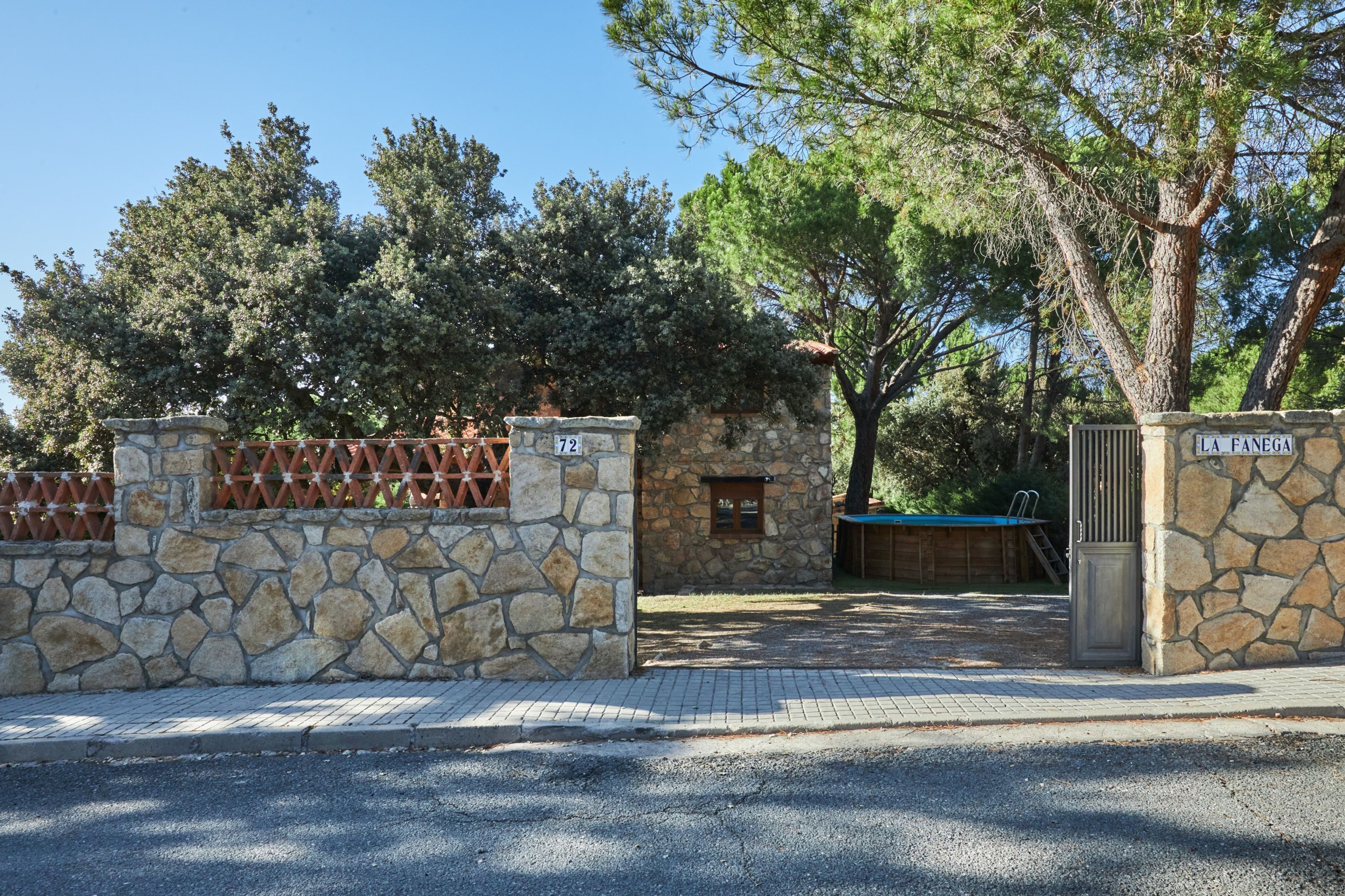 A stone gate with a metal fence, a stone wall, and a wooden door.