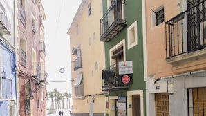 A narrow street lined with colorful buildings, a 'HappyVila' sign, and a 'STOP' sign. - Happy 2 - Estudio Vistas A Calle (Villajoyosa)